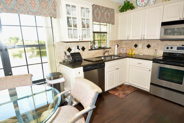 a kitchen with a stove a sink and white cabinets with wooden floor