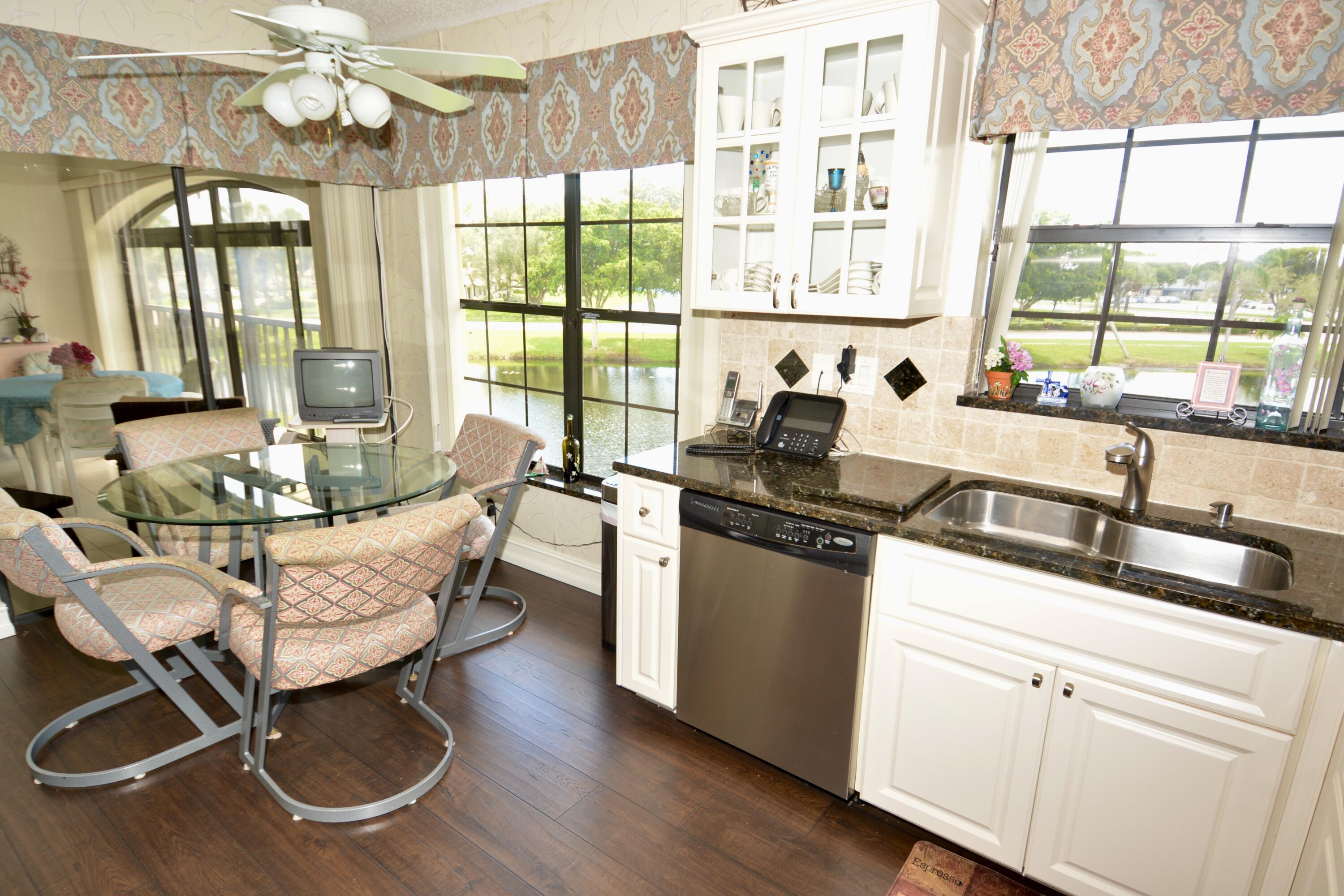 8336 Waterline Drive, Unit 201 Boynton Beach, FL 33472 - Photo 13 of 23 a kitchen with granite countertop a stove a sink and white cabinets with wooden floors