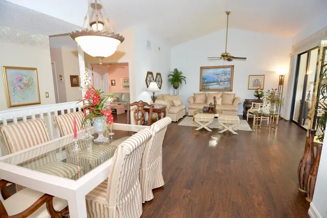 a living room with furniture dining table a chandelier a rug and a large window