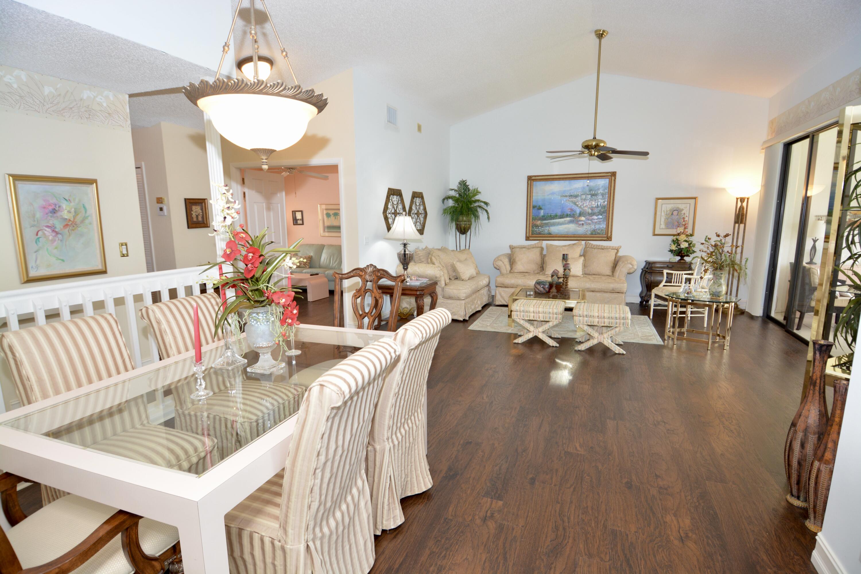 8336 Waterline Drive, Unit 201 Boynton Beach, FL 33472 - Photo 6 of 23 a living room with furniture dining table a chandelier a rug and a large window