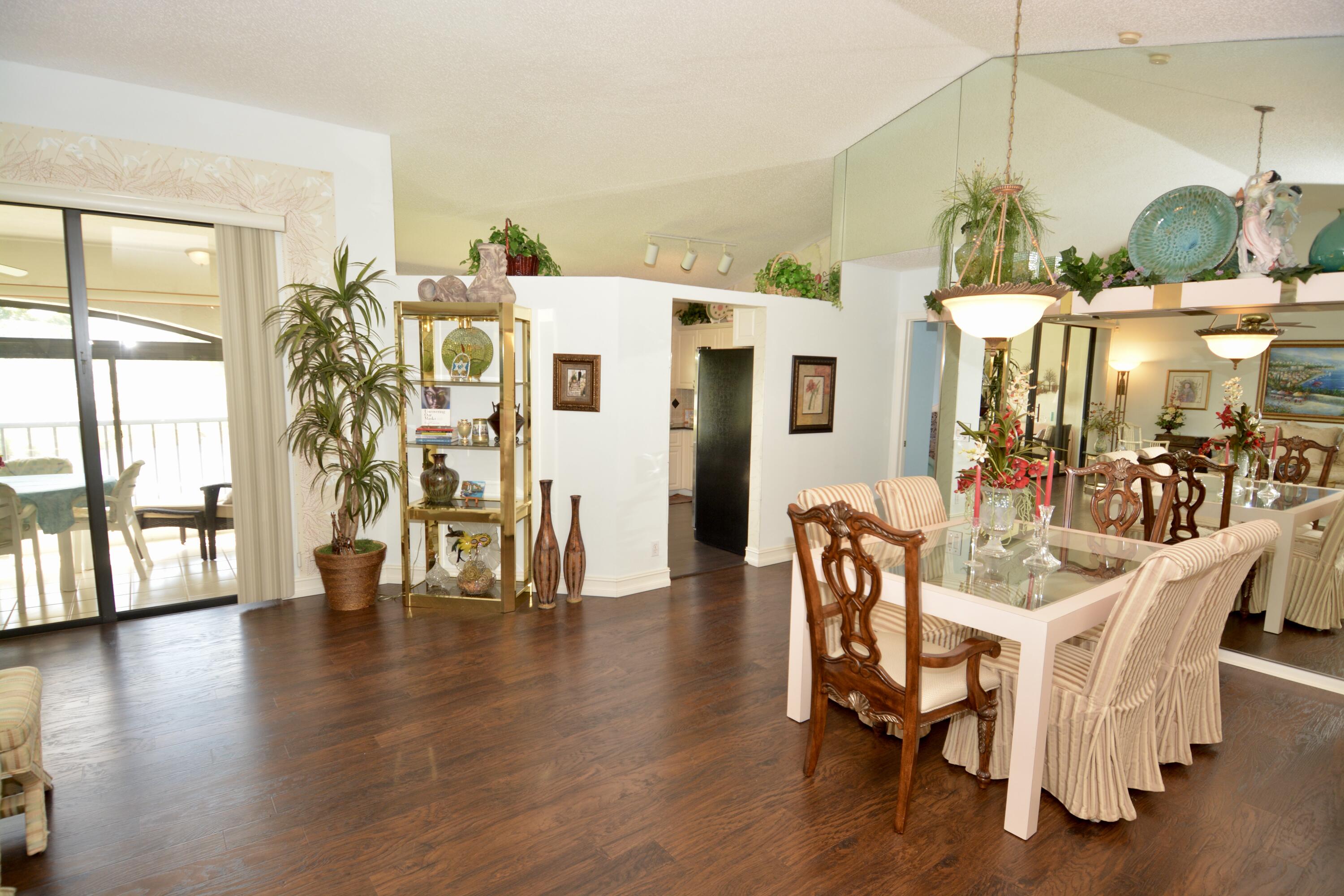 8336 Waterline Drive, Unit 201 Boynton Beach, FL 33472 - Photo 7 of 23 a dining room with wooden floor a chandelier a glass table and chairs