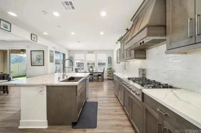 a kitchen with stainless steel appliances granite countertop a stove a sink a refrigerator and white cabinets
