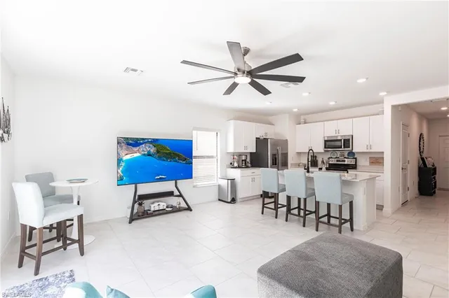 a kitchen with stainless steel appliances kitchen island granite countertop a refrigerator a stove a sink a dining table and chairs with wooden floor