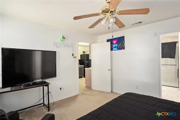 a living room with flat screen tv and a refrigerator