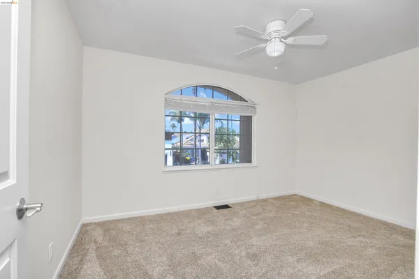 an empty room with a window and a fan