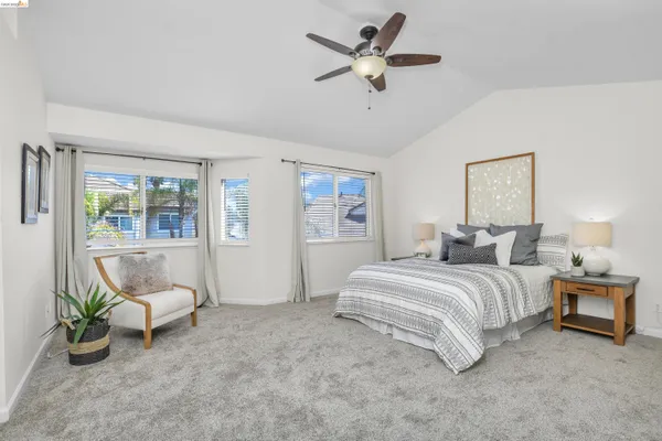 a spacious bedroom that has a bed and ceiling fan