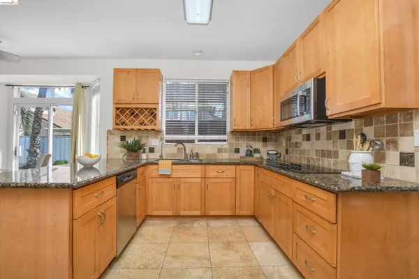 a large kitchen with granite countertop a sink and dishwasher a stove top oven with wooden floor