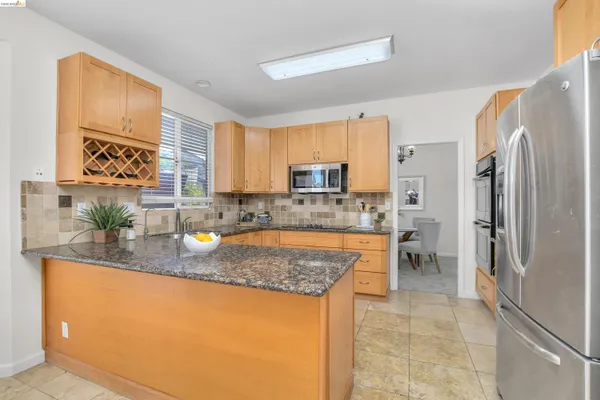 a kitchen with stainless steel appliances granite countertop a refrigerator sink and stove