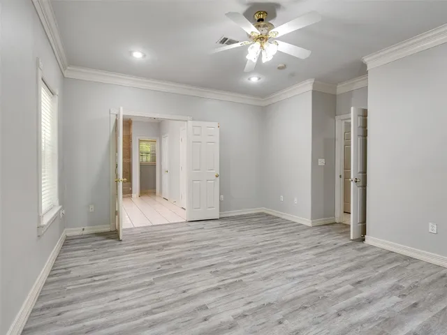 an empty room with wooden floor and ceiling fan