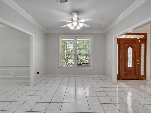 a view of an empty room with window and chandelier fan