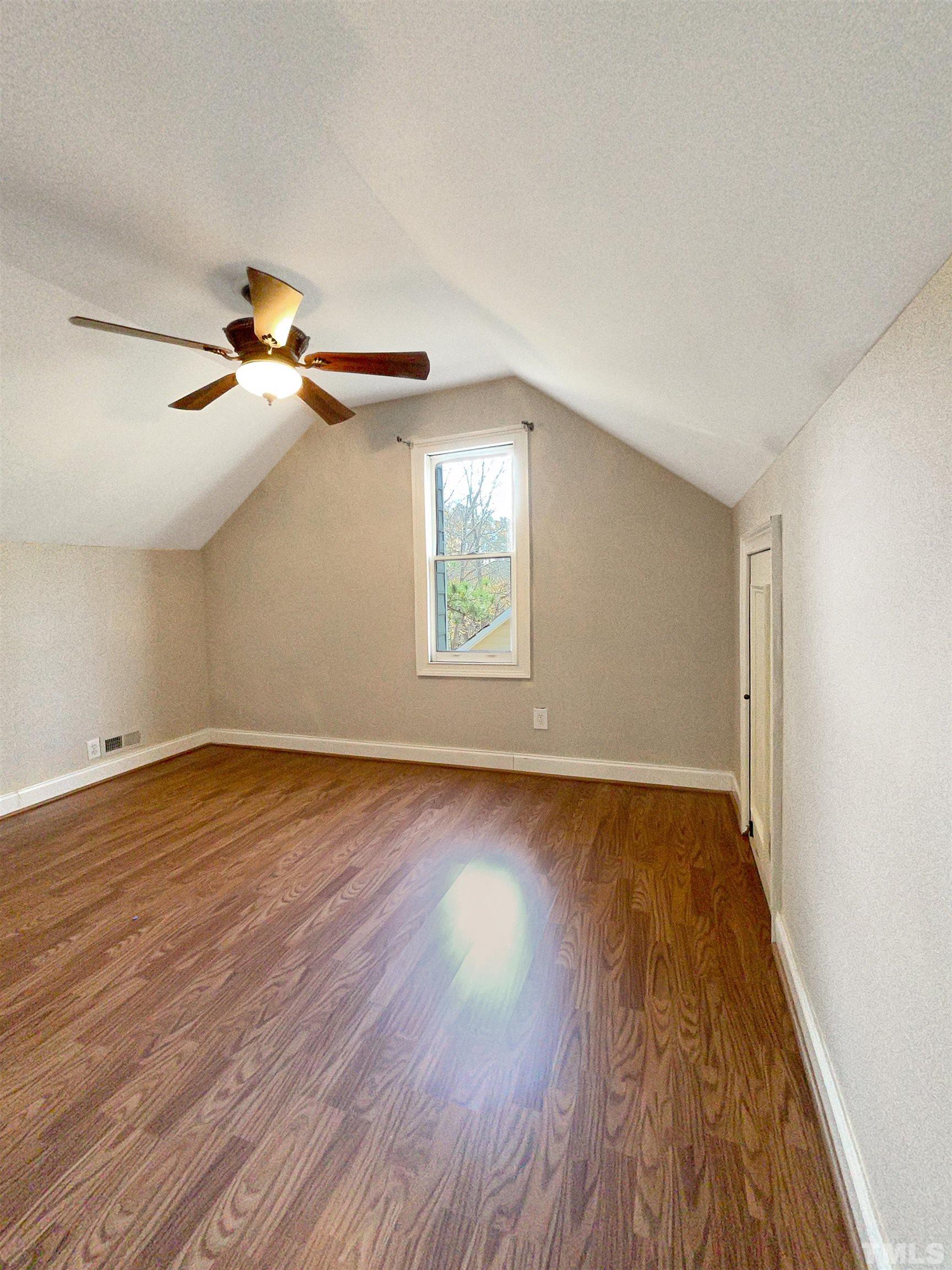6017 Tarleton Court Raleigh, NC 27616 - Photo 20 of 26 an empty room with wooden floor chandelier fan and windows
