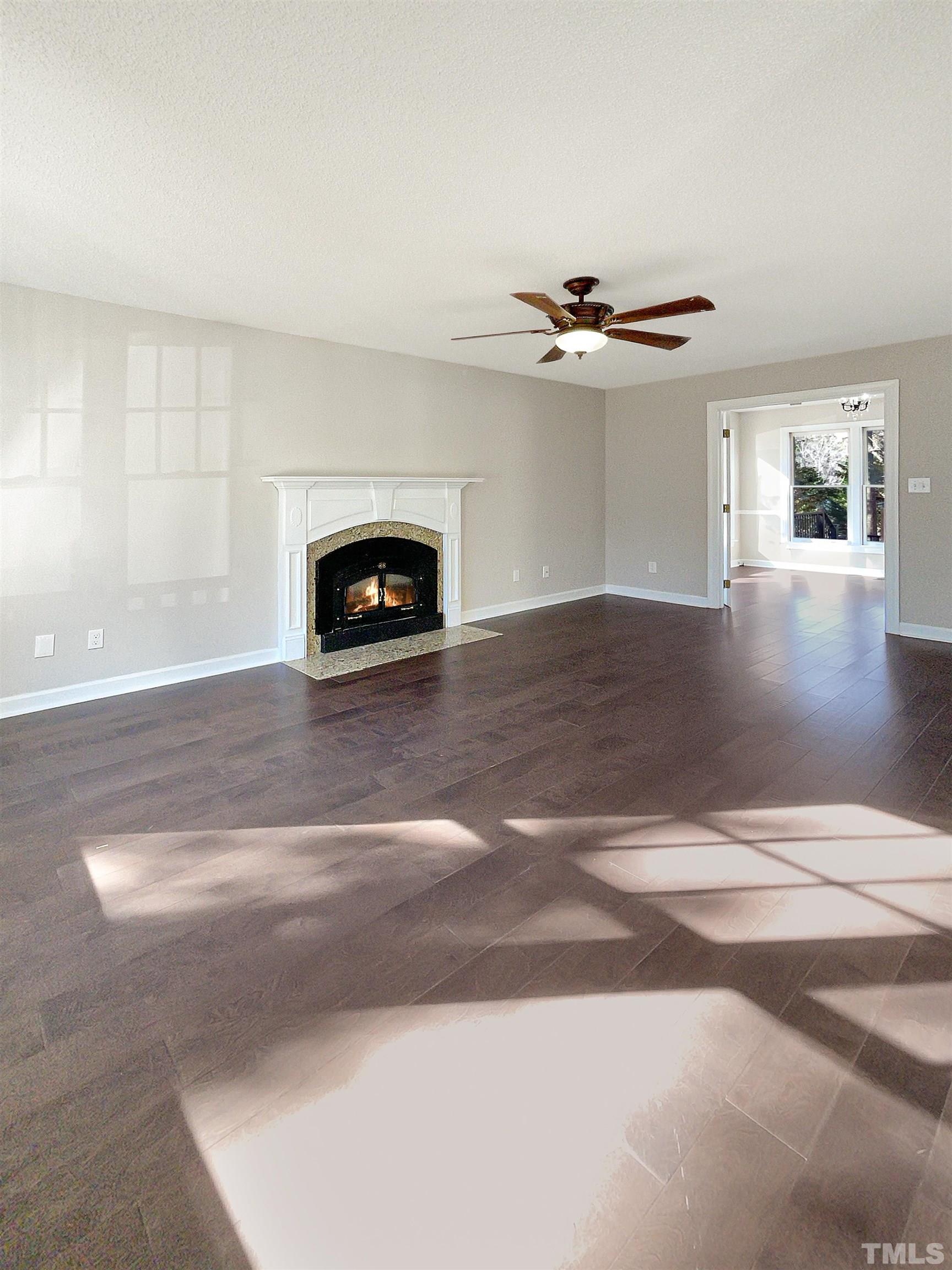 6017 Tarleton Court Raleigh, NC 27616 - Photo 3 of 26 a view of a livingroom with a fireplace a ceiling fan and wooden floor