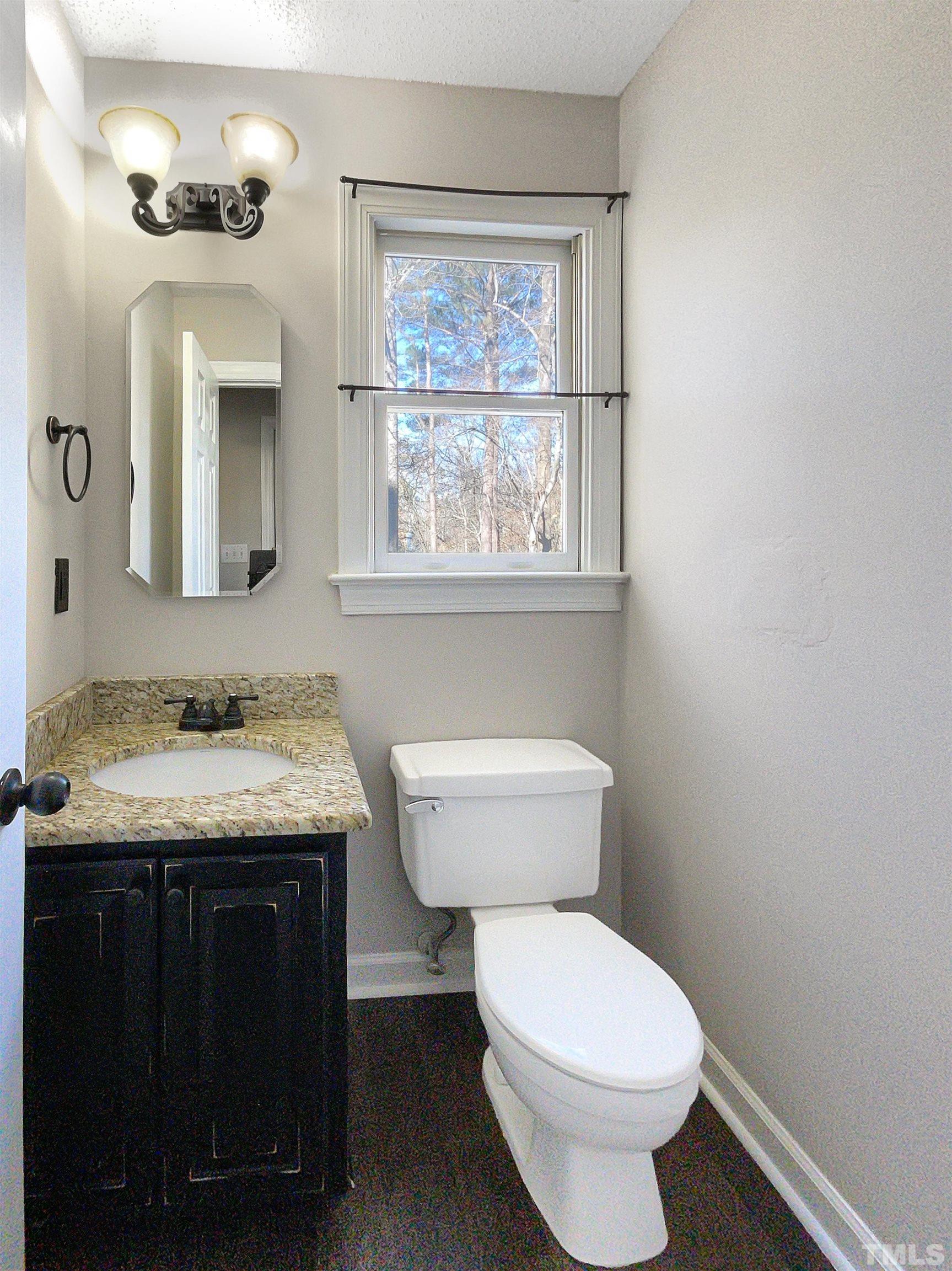 6017 Tarleton Court Raleigh, NC 27616 - Photo 9 of 26 a bathroom with a granite countertop toilet a sink and a window