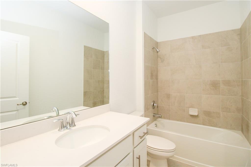 2156 Dragonfruit Way Naples, FL 34120 - Photo 30 of 50 Full bathroom featuring vanity, tiled shower / bath, and toilet