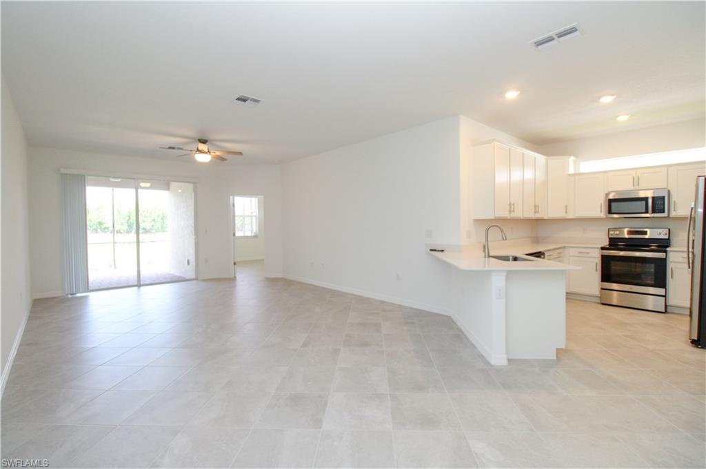 2156 Dragonfruit Way Naples, FL 34120 - Photo 34 of 50 Kitchen with appliances with stainless steel finishes, kitchen peninsula, ceiling fan, and light tile patterned floors