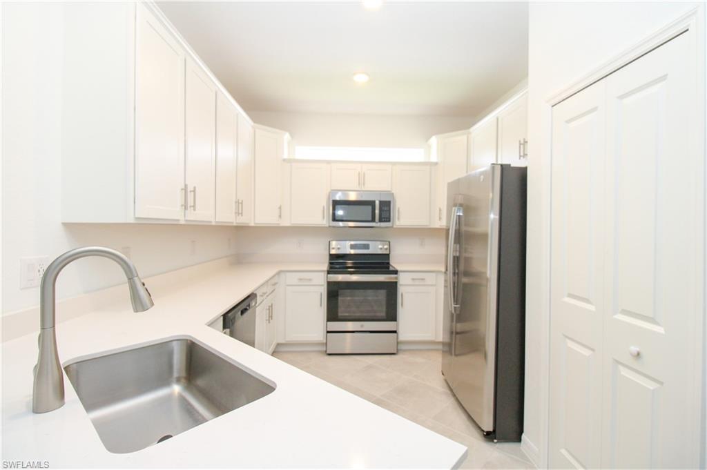 2156 Dragonfruit Way Naples, FL 34120 - Photo 36 of 50 Kitchen featuring sink, light tile patterned flooring, white cabinets, and stainless steel appliances