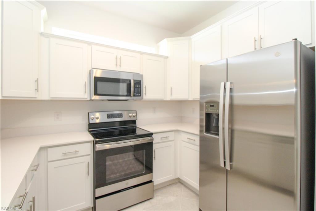 2156 Dragonfruit Way Naples, FL 34120 - Photo 39 of 50 Kitchen featuring appliances with stainless steel finishes, light tile patterned floors, and white cabinets