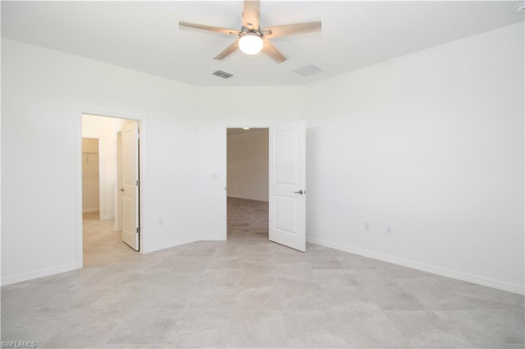 2156 Dragonfruit Way Naples, FL 34120 - Photo 48 of 50 Unfurnished bedroom with light tile patterned floors, a spacious closet, and ceiling fan
