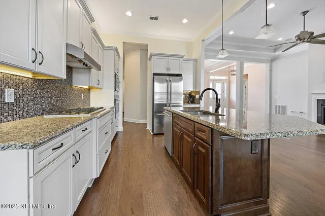 a kitchen with stainless steel appliances granite countertop a sink a stove and a refrigerator