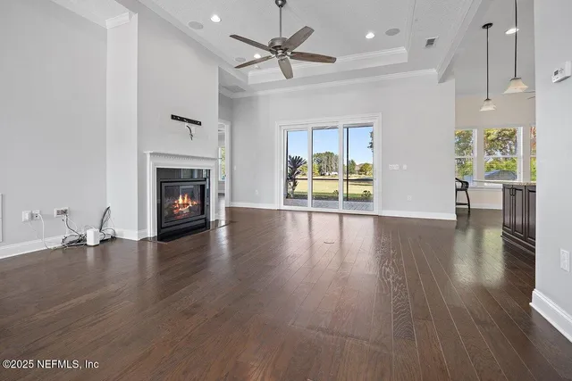 an empty room with wooden floor a fireplace and windows