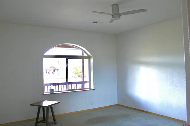 an empty room with wooden floor a ceiling fan and windows