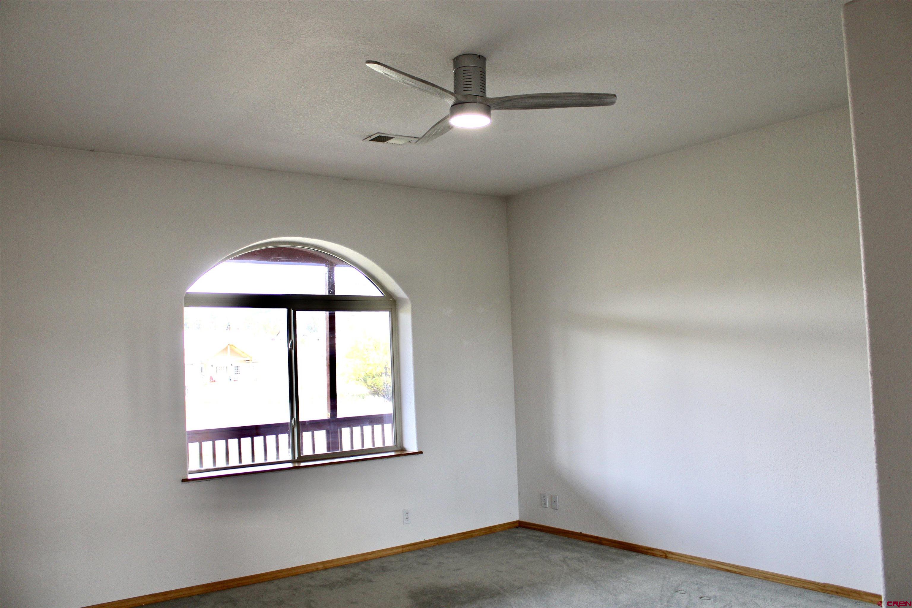 59 Rincon Court Pagosa Springs, CO 81147 - Photo 23 of 37 an empty room with wooden floor a ceiling fan and windows