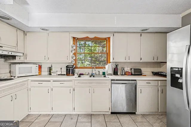 a kitchen with cabinets appliances a sink and a window