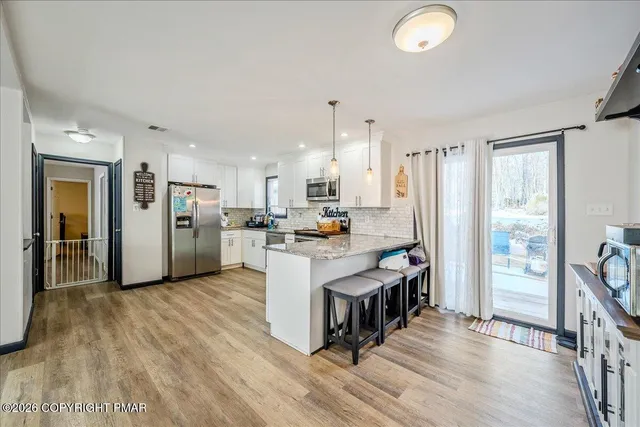 a open kitchen with stainless steel appliances granite countertop a refrigerator oven stove a sink and a dining table with wooden floor