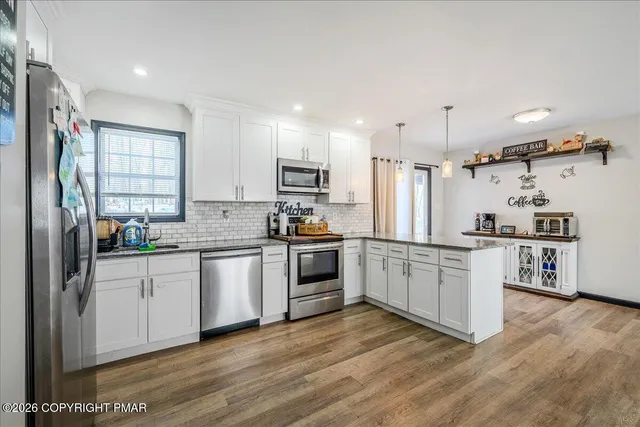 a kitchen with granite countertop a refrigerator oven a sink dishwasher white cabinets and wooden floor