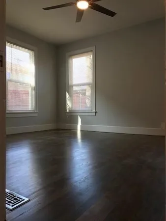 an empty room with wooden floor fireplace and windows