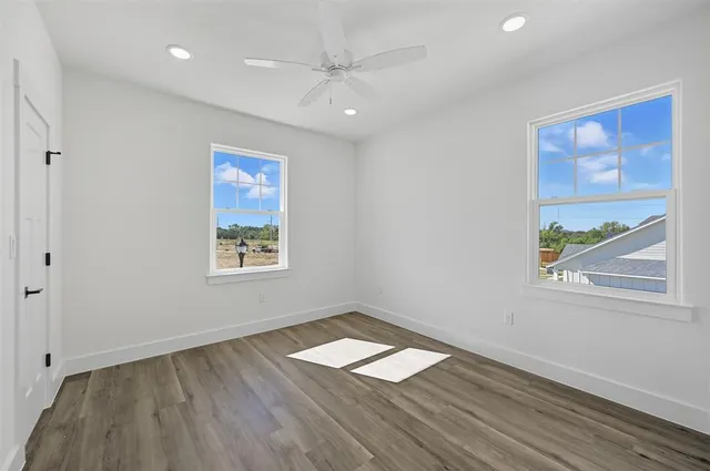 a view of empty room with wooden floor and fan