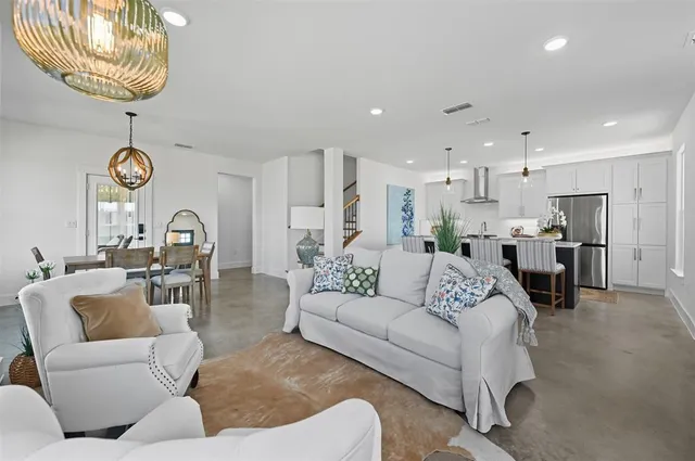 a living room with furniture kitchen view and a chandelier