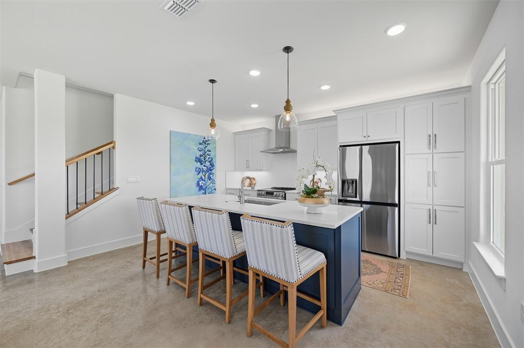 104 Cardinal Wds Granbury, TX 76049 - Photo 8 of 23 Kitchen with stainless steel appliances, a kitchen bar, decorative light fixtures, wall chimney range hood, and white cabinetry
