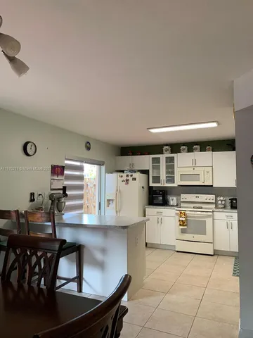 a kitchen with stainless steel appliances granite countertop a stove top oven a sink dishwasher and white cabinets with wooden floor