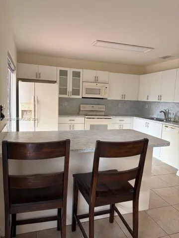 a kitchen with kitchen island a stove a table and chairs in it