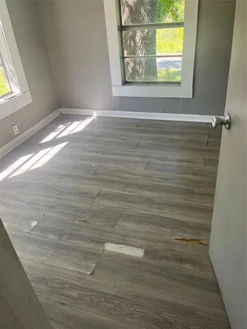 a view of empty room with window and wooden floor