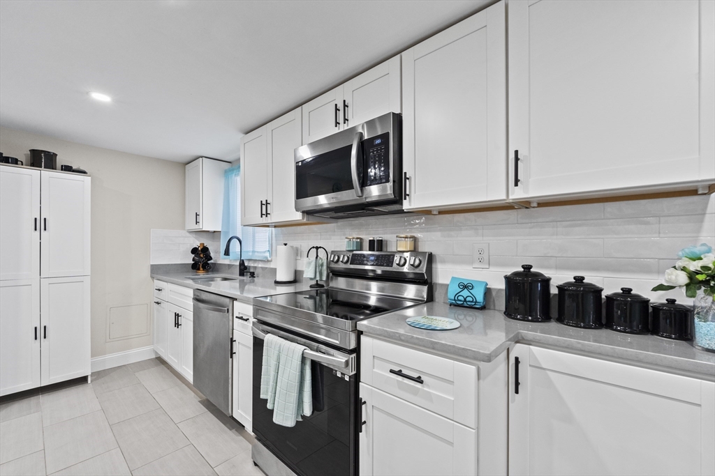 23 Bennett Lane Lancaster, MA 01523 - Photo 8 of 29 a kitchen with stainless steel appliances granite countertop white cabinets a stove a microwave and a sink