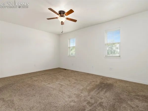 an empty room with a window and a ceiling fan