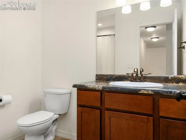 a bathroom with a granite countertop sink a toilet and a mirror