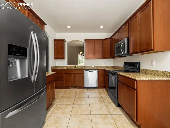 a kitchen with stainless steel appliances granite countertop a refrigerator a sink a stove top oven and a dishwasher