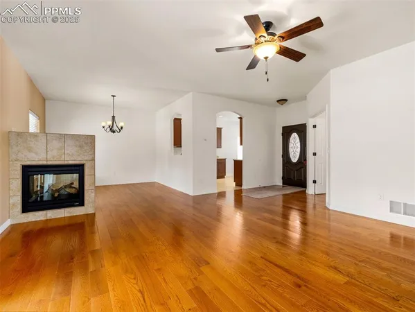 a view of an empty room with a fireplace and wooden floor