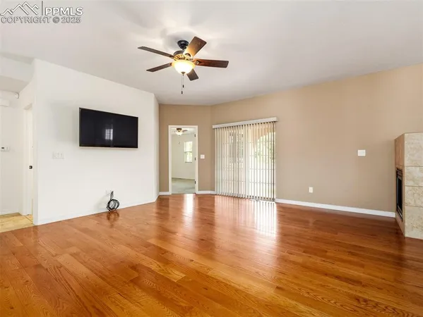 a view of a livingroom with a flat screen tv wooden floor and a ceiling fan