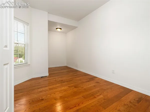 a view of empty room with wooden floor and fan