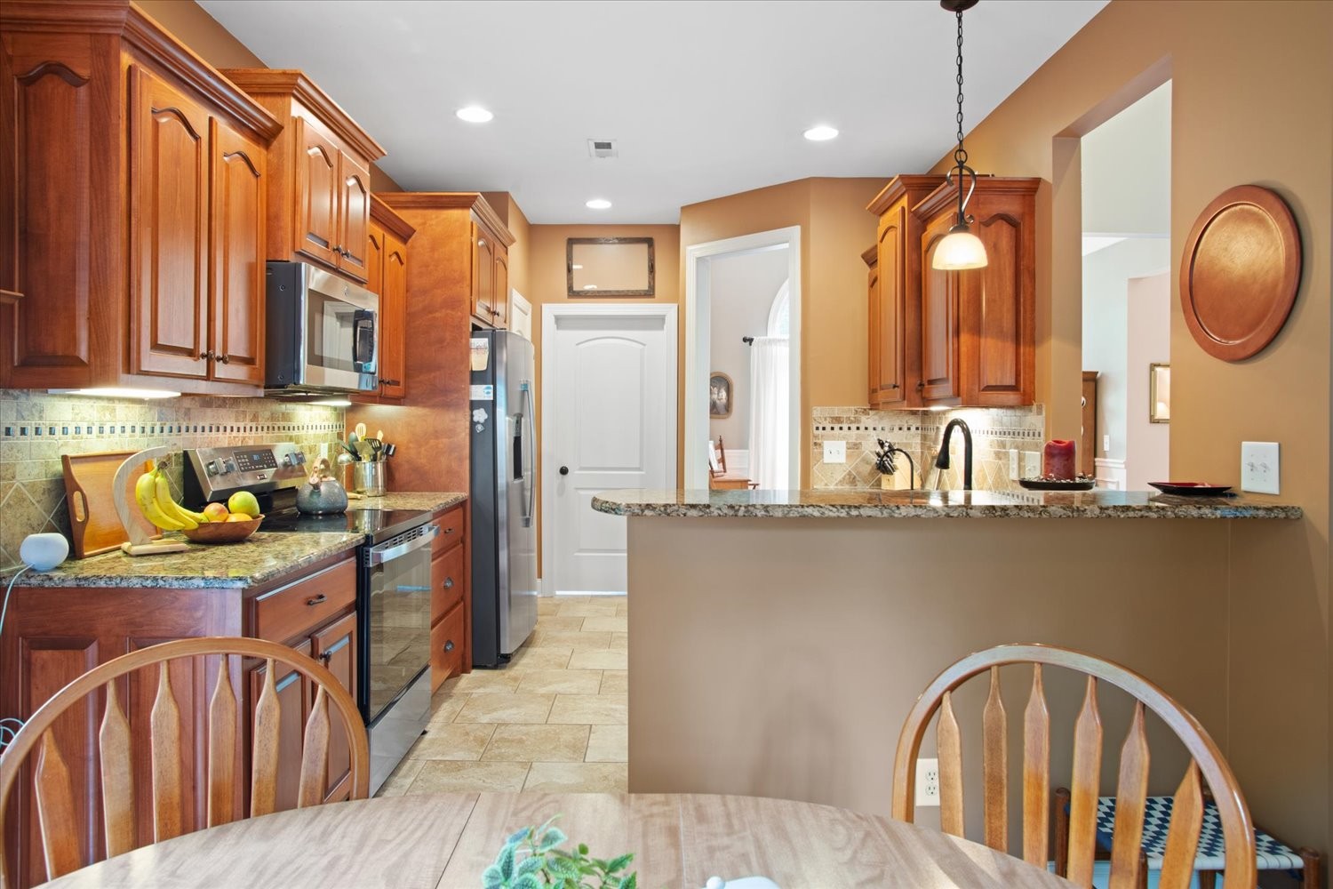 1765 Sugar Ridge Road Spring Hill, TN 37174 - Photo 18 of 44 a kitchen with stainless steel appliances granite countertop a refrigerator a sink dishwasher a stove and a dining table with wooden cabinet