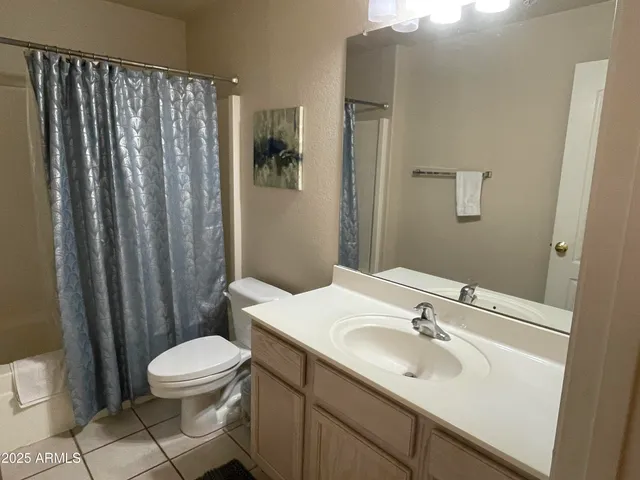 a bathroom with a sink a toilet a mirror and shower curtain