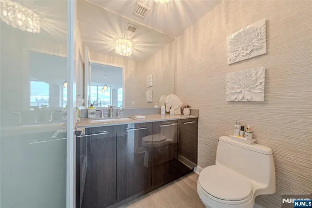 a bathroom with a granite countertop toilet sink and mirror