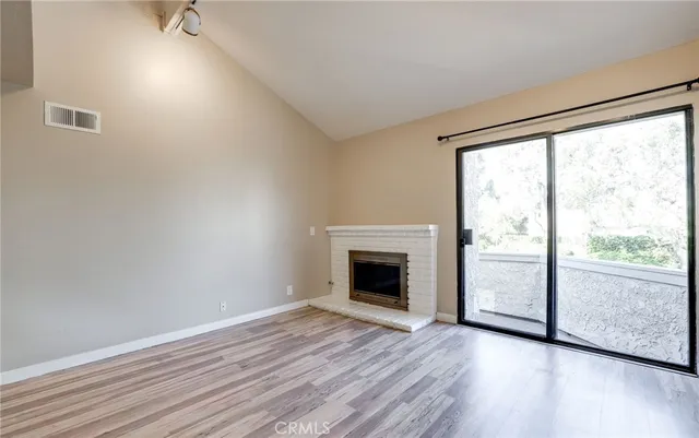 an empty room with wooden floor cabinets and entryway
