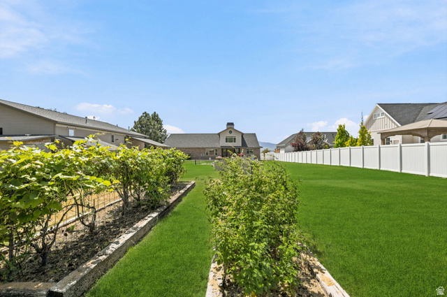 580 North 300 East Logan, UT 84321 - Photo 73 of 74 Expansive backyard featuring a lush lawn, two rows of established garden beds, and a full-height privacy fence
