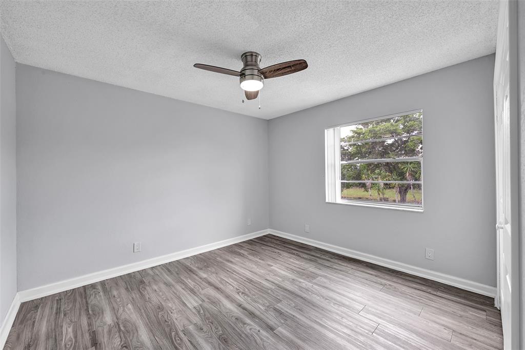 7541 Northwest 16th Street, Unit 1211 Plantation, FL 33313 - Photo 14 of 23 an empty room with wooden floor ceiling fan and windows