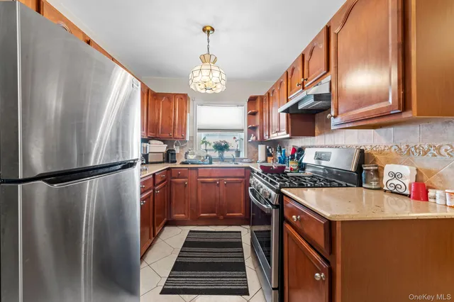 a kitchen with stainless steel appliances granite countertop a refrigerator a sink dishwasher a stove and a dining table with wooden floor